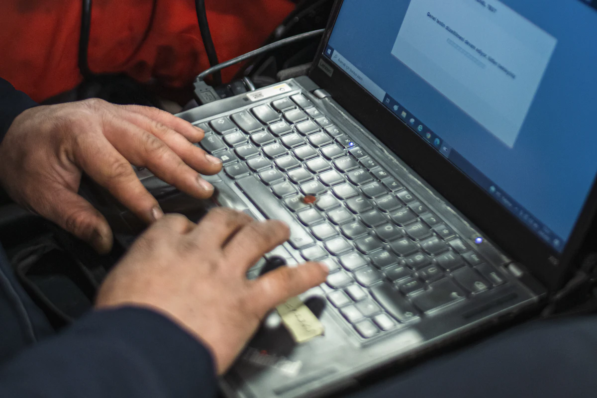 Mechanic running a diagnostic scan on a laptop connected to the car