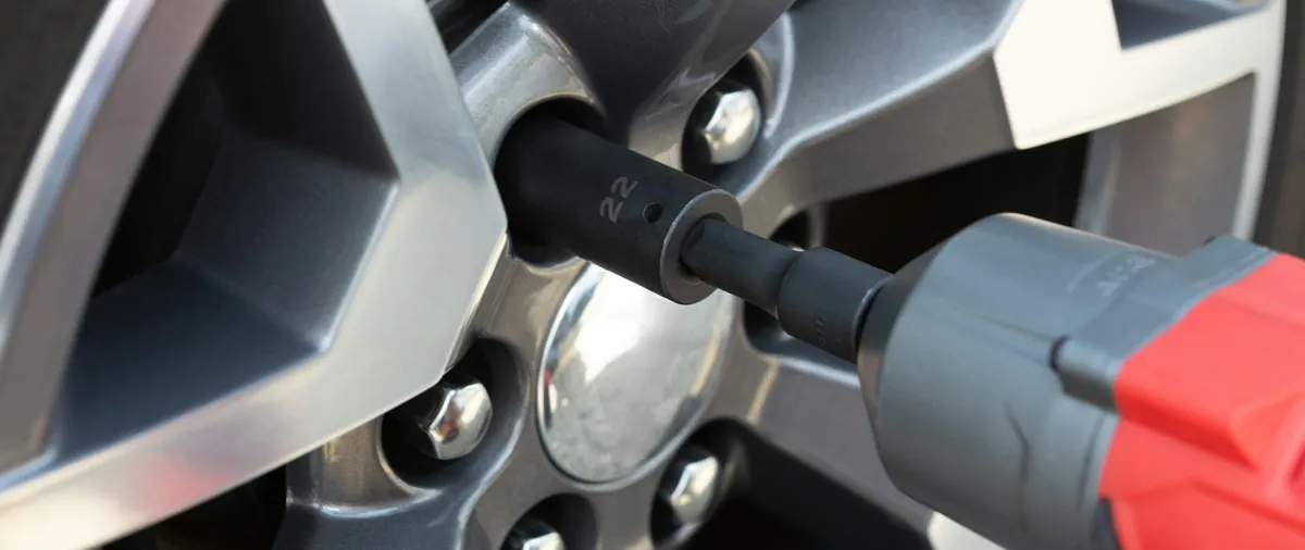 Mobile mechanic removing a wheel with an impact wrench in the driveway