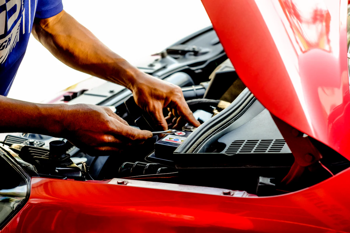 Mechanic working under the open hood of a red car
